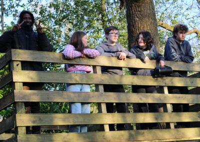 A group of delegates are leaning on a fence, looking down on the camp fire. One of them is making a peace sign with his fingers