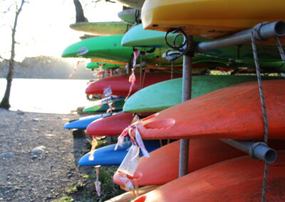 The sun is setting over the lake, there are racks of canoes in the foreground