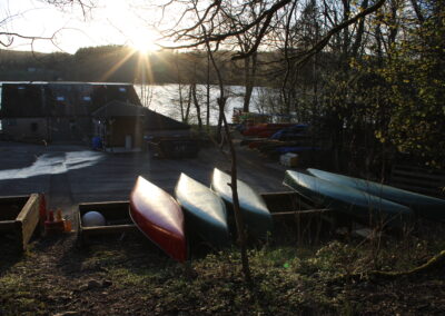 The sun is setting over Lake Windermere, canoes are illuminated in the foreground