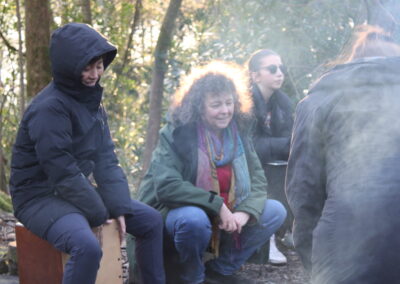Delegates sit around a campfire, the sun is setting, illuminatung the curly hair of one of the delegates