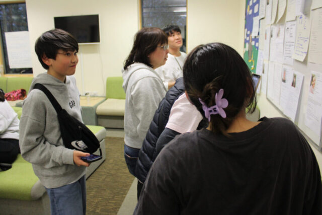 Young Japanese delegates look at profiles on the wall to find out about the other people at the conference