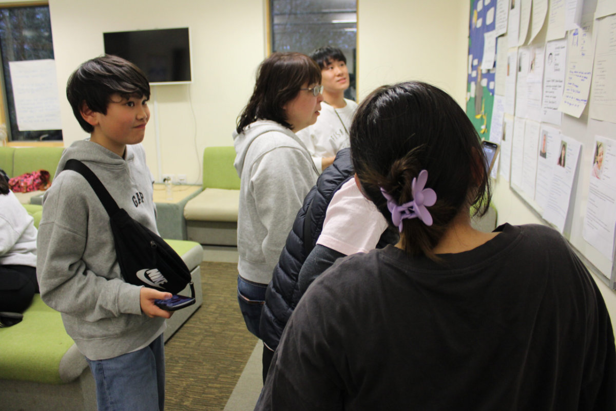 Young Japanese delegates look at profiles on the wall to find out about the other people at the conference
