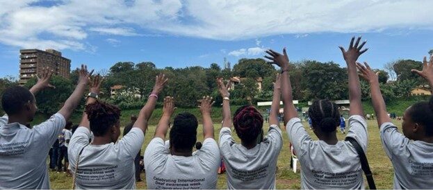 The young researchers from Disabled Inclusive Youth in Uganda look out towards a field where there is a football match taking place.