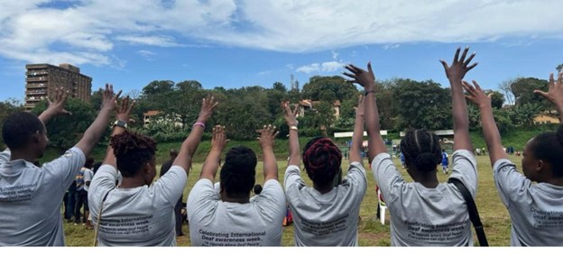 The young researchers from Disabled Inclusive Youth in Uganda look out towards a field where there is a football match taking place.